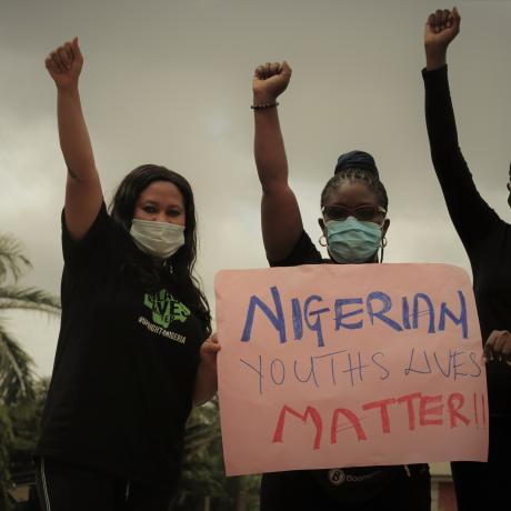 Young women protest against police violence in Nigeria holding a pink sign that says 'Nigerian lives matter'